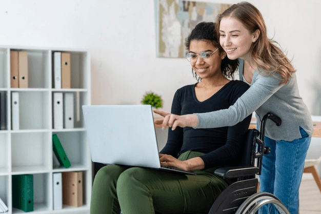 A support worker helping a young woman using a laptop